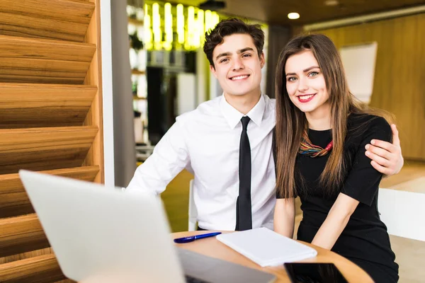 Joven equipo de negocios trabajando juntos en un ordenador portátil sonriendo mientras ven su proyecto llegar a buen término, hombre y mujer — Foto de Stock