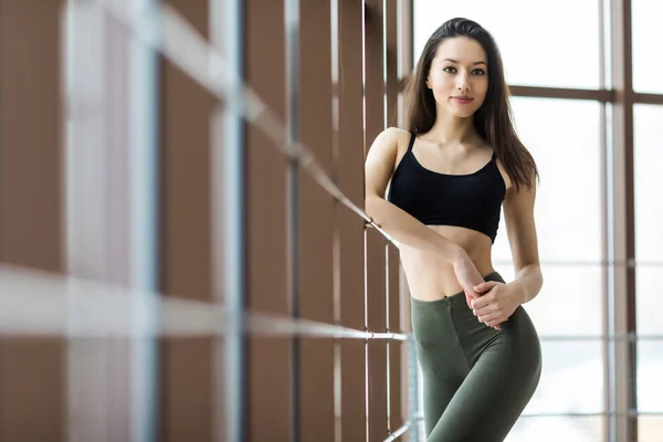 Glückliche junge Frau dehnt sich vor dem Laufen im Fitnessstudio — Stockfoto