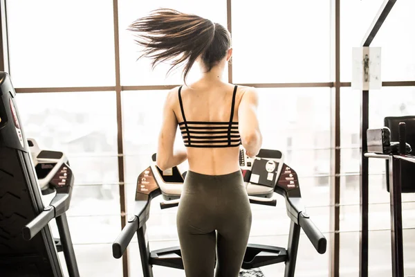 Horizontale schot van vrouw joggen op een loopband op fitnessclub. Vrouw uit te werken in een sportschool op een loopband. — Stockfoto
