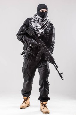 Terrorist holding a machine gun in his hands isolated over white clipart