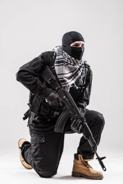 Terrorist holding a machine gun in his hands isolated over white clipart