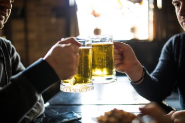 Erkek el, bira bardakları tokuşturup yakın bar veya pub