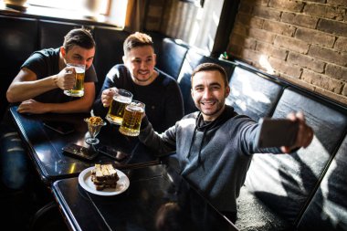 Yakışıklı arkadaş bira içme selfie yapıyor ve barda oturan gülümsüyor. Bira zamanı.