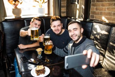 Yakışıklı arkadaş bira içme selfie yapıyor ve barda oturan gülümsüyor. Bira zamanı.