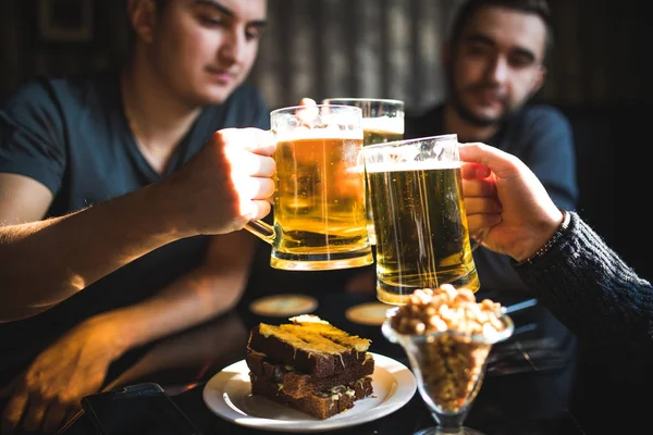 Happy male friends drinking beer and clinking glasses at bar or pub