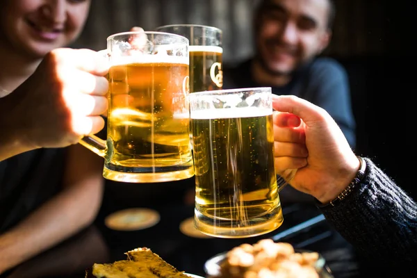 Närbild på klingande glas öl av tre vänner i puben — Stockfoto