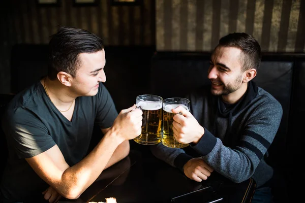 Dois jovens sentados no pub, comendo e bebendo cerveja no pub — Fotografia de Stock