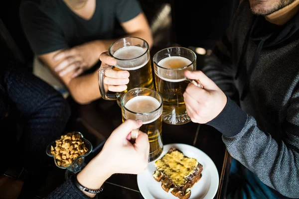 Primer plano de manos masculinas tintineo vasos de cerveza en el bar o pub — Foto de Stock