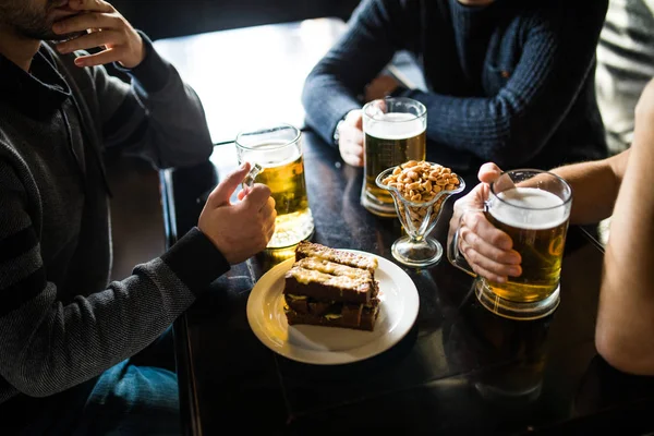 Primer plano de manos masculinas tintineo vasos de cerveza en el bar o pub — Foto de Stock