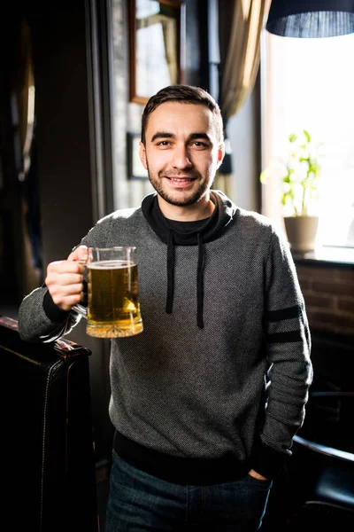 Homem solteiro em um pub ou bar segurando caneca a cerveja alta no ar para aplausos — Fotografia de Stock