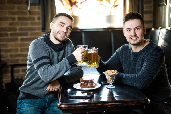 Dois amigos bonitos num bar com copos de cerveja. Hora dos amigos . — Fotografia de Stock