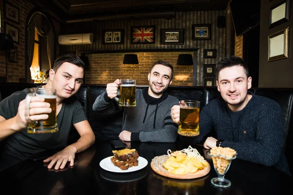 Jovens amigos homens com cerveja no pub e aplausos e comer snaks — Fotografia de Stock