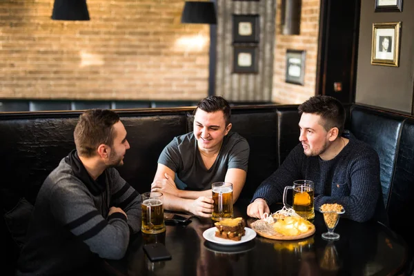 Encontro no pub. Três amigos felizes bebendo cerveja no pub tradicional — Fotografia de Stock
