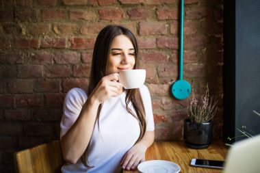 Çay içme ve onun iş molası sırasında onu serbest zaman, güzel iş kadın yemeği modern Café tadını çıkarırken bir gülümseme kahvehane pencereden dışarı bakarak genç güzel kadın portresi