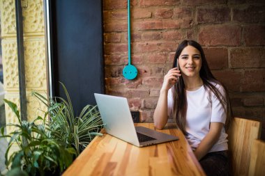 Cep telefonu üzerinde konuşurken ve kafe dükkanda dizüstü kullanarak genç kadın