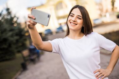 Selfie ile cep telefonu elinden güneşli şehirde sokak alarak genç güzellik kadın.