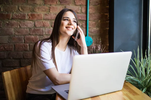 Retrato de una mujer bonita hablando por teléfono mientras está sentada en la cafetería y disfrutando del café — Foto de Stock