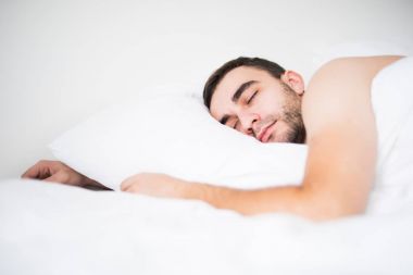 Genç adam yatağında sarılmak yastık, uyku rüya.