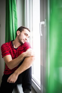 Sabah pencerenin kenarında duran genç adam