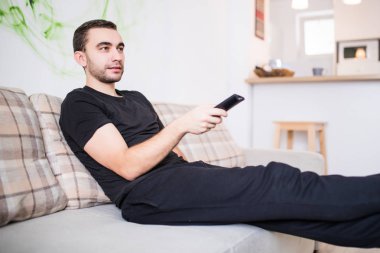 Yakışıklı adam evde kanepe üzerinde Uzaktan kumanda ile