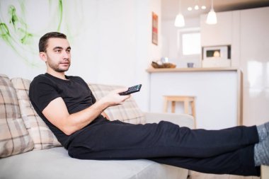 Yakışıklı adam evde kanepe üzerinde Uzaktan kumanda ile