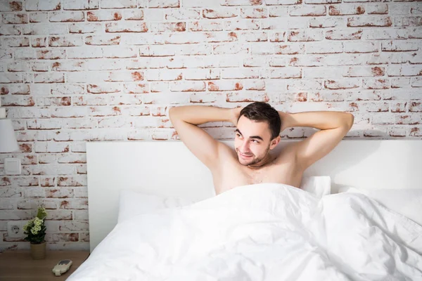 Мечтательный мужчина просыпается утром в спальне — стоковое фото