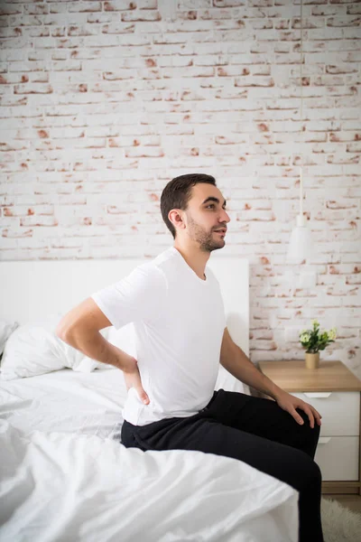 Mann wacht morgens auf und spürt Schmerzen im Bett — Stockfoto