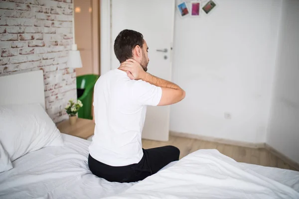 Jeune homme souffrant de maux de cou au lit à la maison — Photo