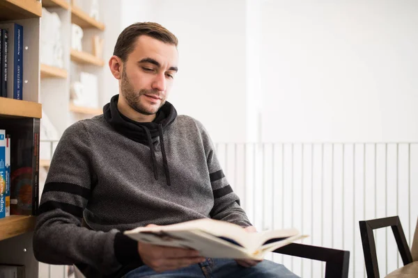 Yakışıklı erkek öğrenci bir kitapçı yerde oturup kitap okumak — Stok fotoğraf