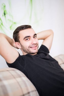 Adam evde koltukta yalan başının arkasında elleriyle