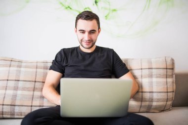 gülümseyen adam evde laptop ile çalışma