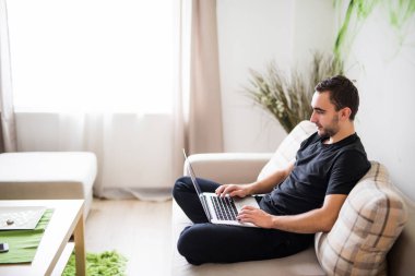 Genç adam ile bir laptop evde kanepede rahatlatıcı