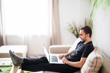 Genç adam ile bir laptop evde kanepede rahatlatıcı