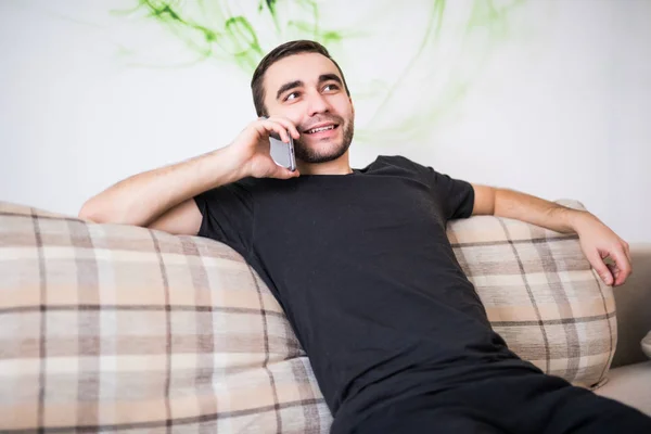 Красивый мужчина на телефоне сидит в гостиной — стоковое фото