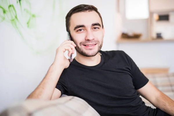 Красивий чоловік на мобільному телефоні сидить у вітальні — стокове фото