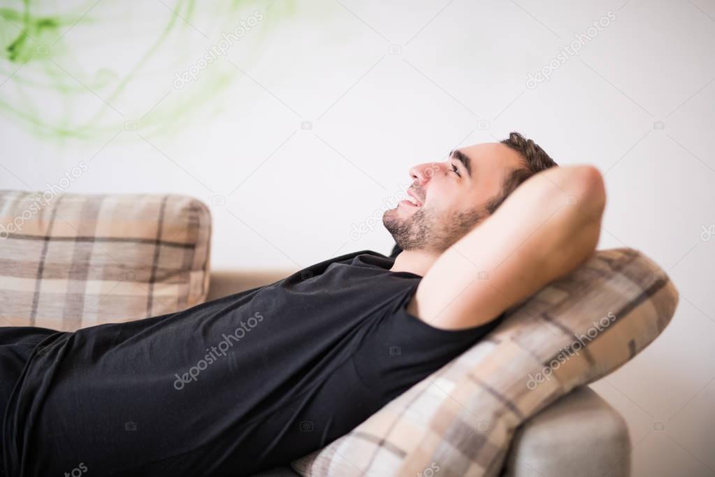 Side view Man lying and relaxing on the couch at home in the living room