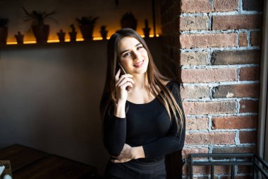 Çekici kız portresi biliyor cep telefonu pencere tuğla duvar arka planda yakınındaki