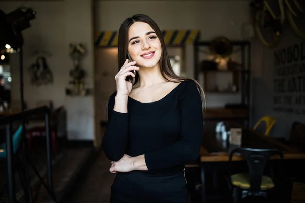 Νεαρά ομορφιά χαμογελαστό γυναίκα στέκεται σε ένα καφέ και να μιλάμε για το κινητό τηλέφωνο — Φωτογραφία Αρχείου