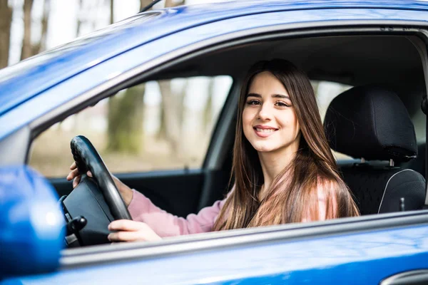 Une jeune femme conduisant une voiture en ville. Portrait d'une belle femme dans une voiture, regardant par la fenêtre et souriant. Concepts de voyage et vacances — Photo