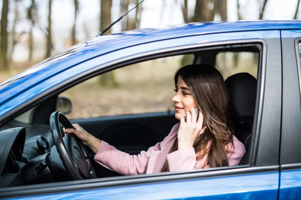 Jovem com a mão no volante usando o telefone celular enquanto dirige na estrada — Fotografia de Stock