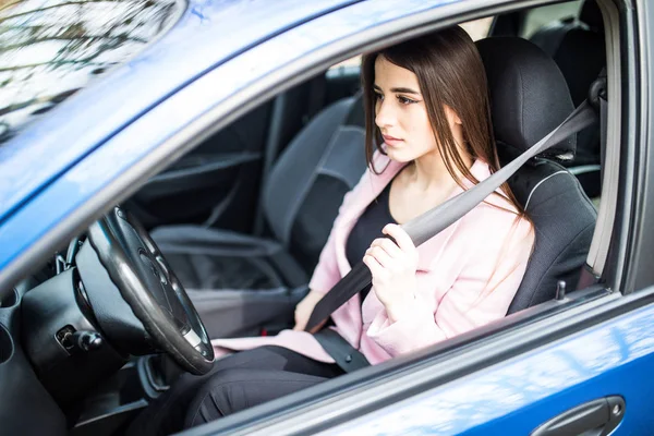 Retrato de mujer joven abrocharse el cinturón de seguridad en su coche — Foto de Stock