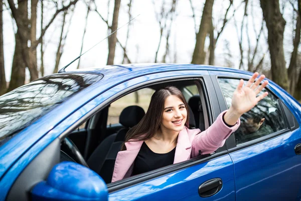 Femme heureuse chauffeur assis dans la voiture faire un geste de salut sur la route — Photo