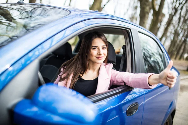 Mulher sentada no carro e mostrando os polegares na estrada — Fotografia de Stock