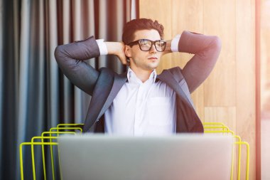 Relax zamanı. Genç, mutlu işadamı ofisinde rahatlatıcı.