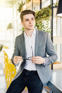 Onun kollarında kameraya ciddi görünümlü ahşap masanın kenarında oturan gözlüklü genç işadamı