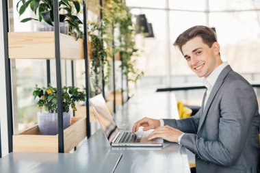 Genç adam ofis, masada oturan dizüstü bilgisayar üzerinde çalışan.