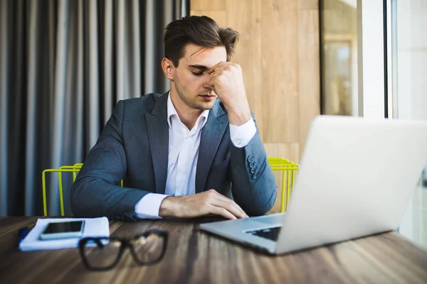 Розчарований молодий бізнесмен працює на ноутбуці в офісі — стокове фото