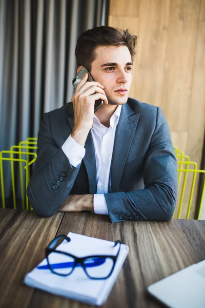 Молодий бізнесмен кавказький у своєму офісі по телефону перед записником — стокове фото