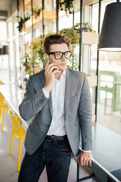 Красивий молодий позаштатний бізнесмен говорить по телефону в сучасному офісі — стокове фото