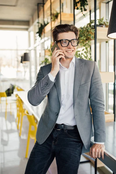 Przystojny, młody biznesmen w garnitur i okulary, mówiąc na telefon w biurze — Zdjęcie stockowe
